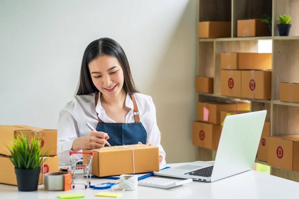 Asian small business owner holds a pen to write down addresses to deliver parcels to customer
