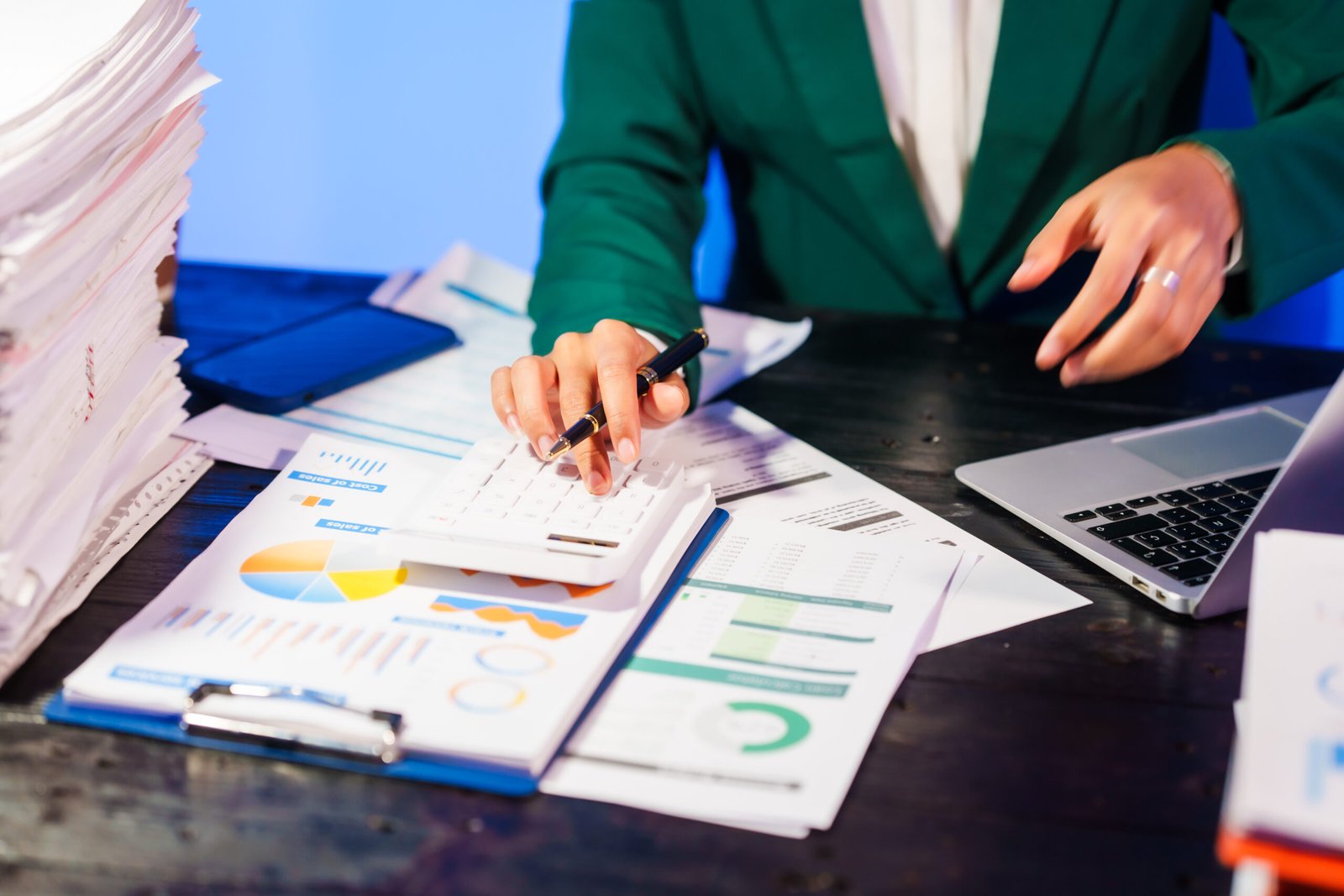 Professional reviewing financial reports with a calculator and laptop