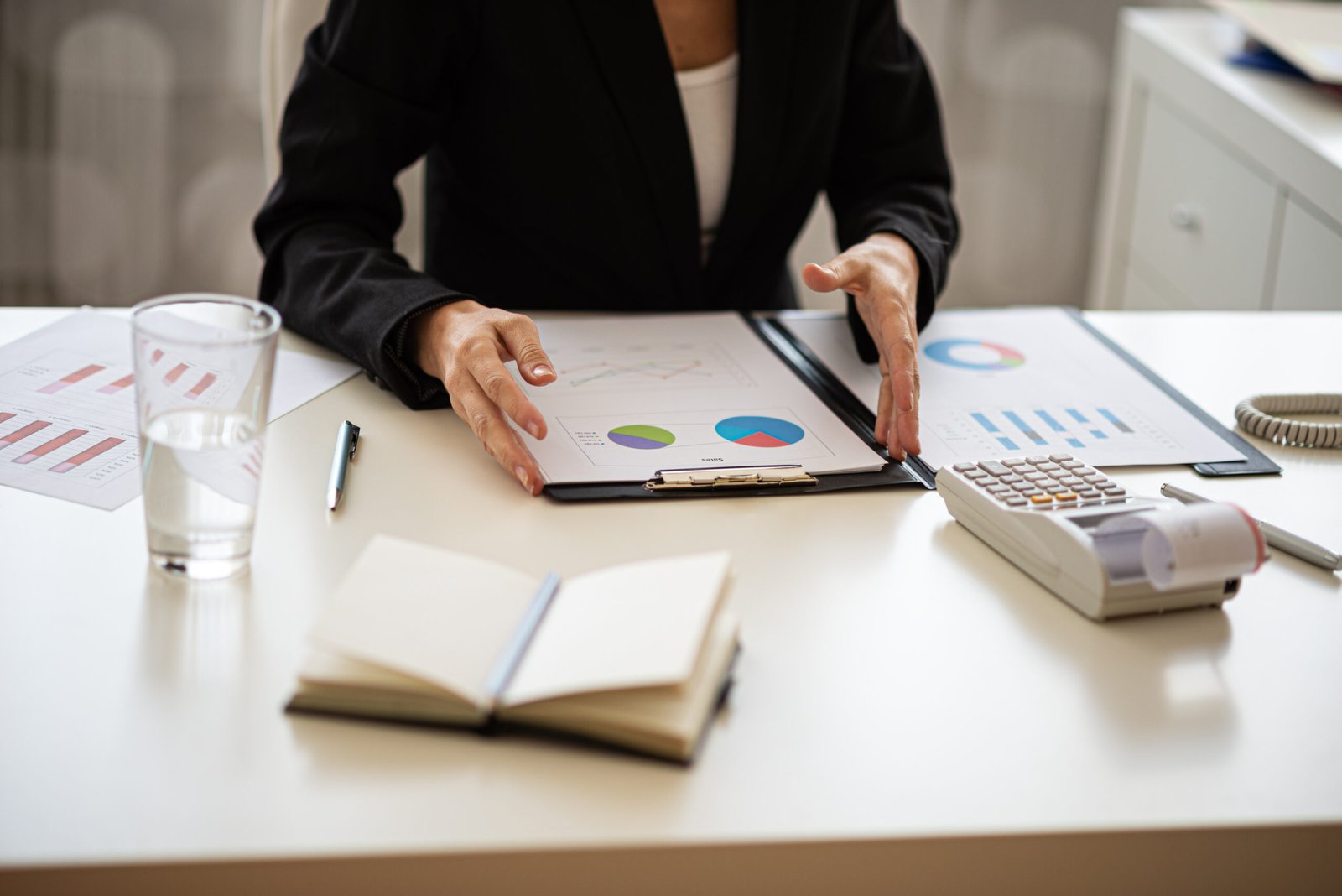 Woman reviewing printed financial charts beside a calculator
